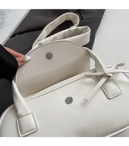 Detailaufnahme des Magnetverschlusses der cremeweißen Schultertasche mit Schleife