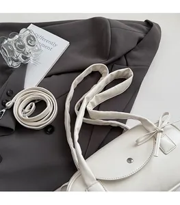 Detail der cremefarbenen Kissen-Tasche aus Leder mit Schleife und zwei Schultergurten