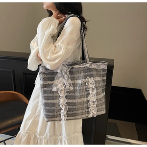 Détail du sac cabas à carreaux gris avec bordures en dentelle blanche et nœud latéral