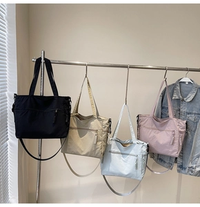 Waterproof nylon tote bags in four colors hanging on a rack with adjustable straps