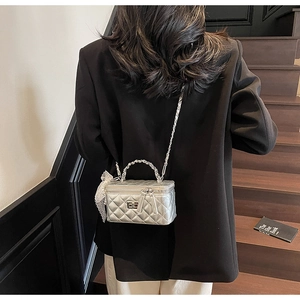 Detailed view of silver quilted vanity bag with metal clasp and lace bow charm