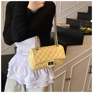 Close-up of light yellow quilted leather bag with silver chain and metal turn-lock