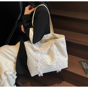 Détail du sac cabas blanc à pois noirs avec des bordures en dentelle et des volants
