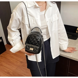 Detail of black quilted leather mini backpack with silver chain strap and polished finish
