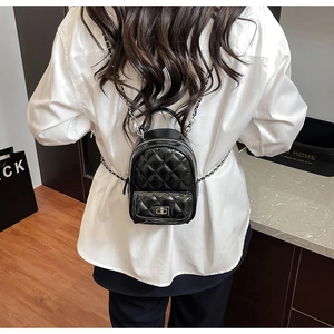 Detail of black quilted mini backpack with silver chain straps and metallic turn-lock