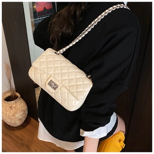 Detail of quilted leather flap bag with metal turn-lock and chain strap in cream finish