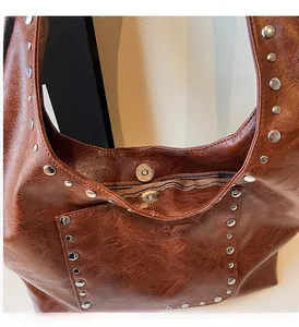 Détail du cabas marron foncé avec rivets métalliques et fermeture magnétique sur cuir vintage