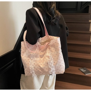 Détail d'un sac cabas rose à pois avec volants en dentelle blanche et bandoulière
