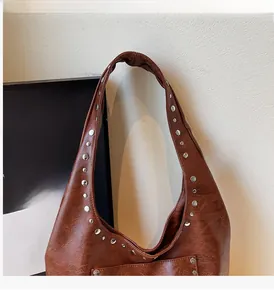 Gros plan sur l'anse renforcée et les rivets argentés de ce sac fourre-tout en cuir brun