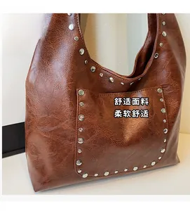 Détail du sac hobo en similicuir marron avec des rivets argentés et texture vintage