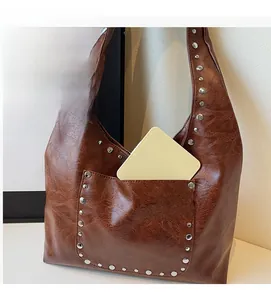 Détail d'un sac hobo en cuir marron avec des rivets argentés et une poche frontale