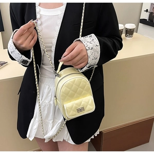 Close-up of yellow quilted leather mini backpack with metal chain strap and turn-lock