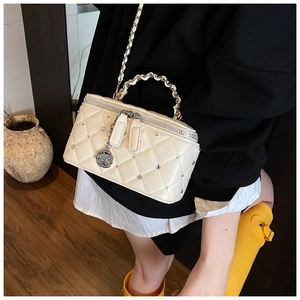 Detail of cream quilted crossbody bag with stud accents and silver rose pendant charm
