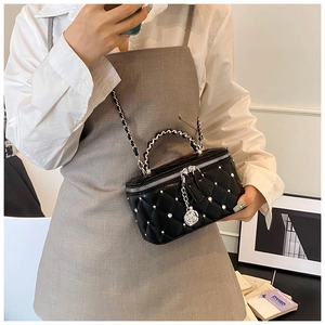 Detail of quilted leather crossbody bag with silver studs and camellia zipper pull