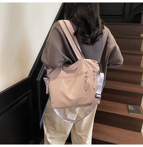 Large pale pink nylon tote bag shown on shoulder with adjustable strap and multiple pockets