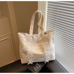 Vue détaillée du sac cabas en toile blanche à pois noirs avec décoration de nœud en dentelle