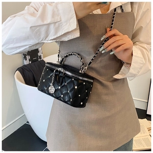 Detail of black quilted leather crossbody bag with pearls and camellia charm