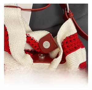 Detail of metal magnetic clasp on red and white woven crochet tote bag with leather strap