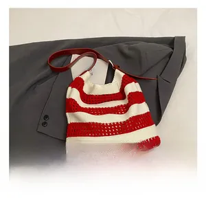 Detail of red and white striped knit tote bag with adjustable leather strap
