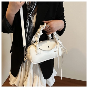 Detail der weißen Zylindertasche mit Scrunchie-Griff und modischen Lederbändern