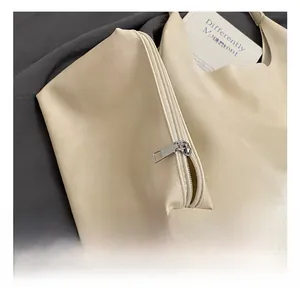 Detail of creamy PU leather tote bag showing pebble texture and silver hardware