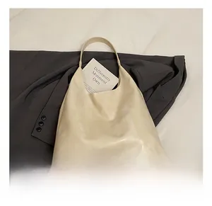 Detail view of cream-colored leather hobo bag placed on a grey blazer for daily commuting