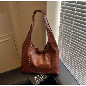 Détail du sac cabas vintage marron avec rivets métalliques sur cuir synthétique lisse