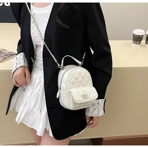 Close-up of white quilted mini backpack with silver chain strap and metal turn-lock detail