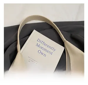 Detail of light beige leather tote featuring premium pebble texture and seamless stitching