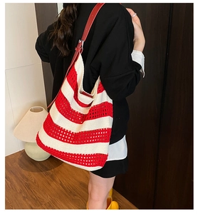 Detail view of woven knit tote bag with red and white stripes and red leather strap
