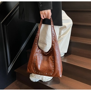 Détail du sac vintage marron avec clous argentés et texture sur escaliers en bois