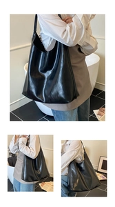 Detail showing the glossy black large tote bag with its wide shoulder strap and soft texture