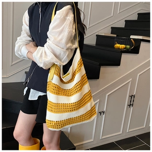Detail of yellow and beige striped crochet tote bag with leather straps on a model