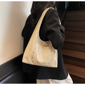 Détail du sac crème avec rivets argentés et texture de cuir synthétique plissé