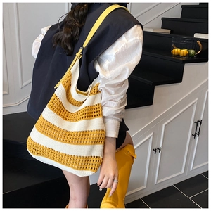 Close-up of yellow and beige hand-woven crochet tote bag with leather shoulder strap