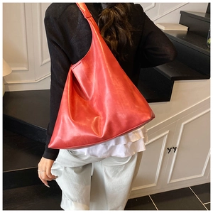 Detail view of a bright orange minimalist leather tote bag with a wide shoulder strap