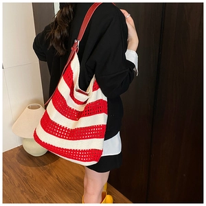 Detail of red and white crochet tote bag showing woven texture and leather strap buckle