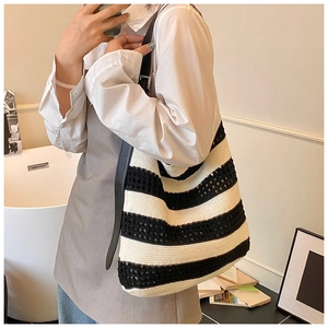 Detail of black and white striped woven tote bag with hollow texture and leather strap