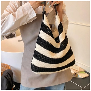 Close-up of black and white striped knit tote with adjustable black leather strap