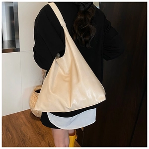 Detailed view of spacious off-white tote bag with wide shoulder strap on model