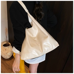Detailed view of spacious off-white tote bag in soft leather shown on shoulder