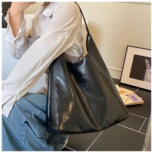 Detailed view of glossy black leather tote bag with wide shoulder strap texture