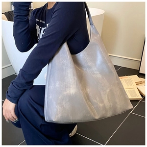 Silver metallic tote bag shown on model in a minimalist modern indoor setting