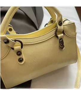 Detailansicht der gewellten Faltentextur und dunklen Metallnieten an der gelben Tasche