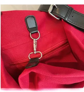 Detail of premium silver metal buckle and black leather strap on a red canvas bag