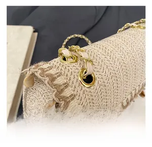 Detail of straw woven bag with light gold eyelets and metal chain leather strap