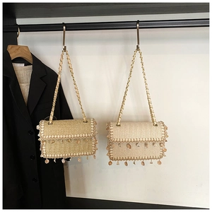Detail of woven straw shoulder bags with gold chain straps and shell fringe ornaments