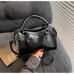 Detail der schwarzen Handtasche aus Kunstleder mit Crinkle-Struktur und Metallnieten