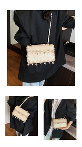 Detail of beige straw crossbody bag with teardrop tassels and gold chain strap