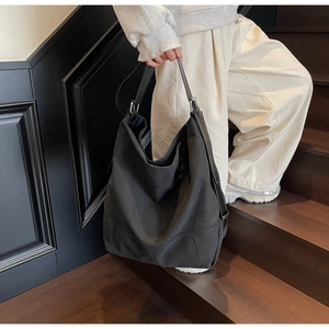 Minimalist black canvas tote bag with adjustable shoulder strap shown on a model